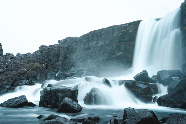 Waterfall crashing into the water below with beautiful cliffs in the back