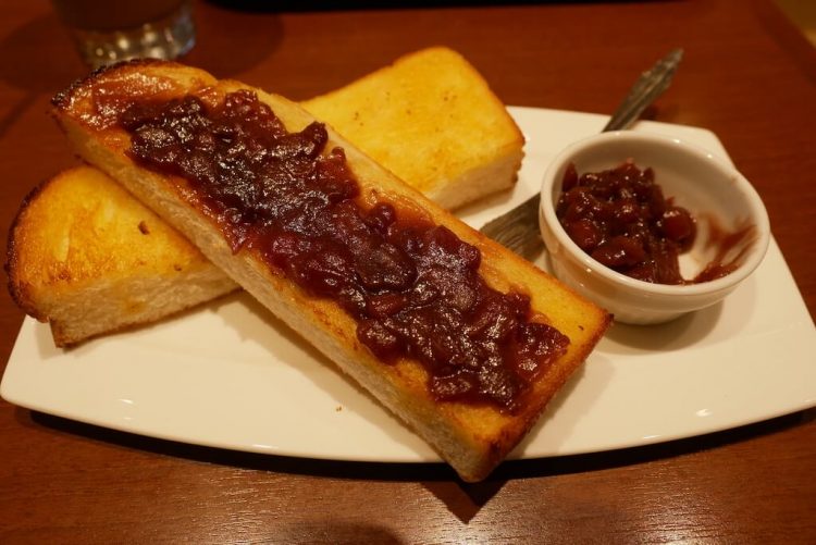 baguette style bread cut open with red spread on white plate