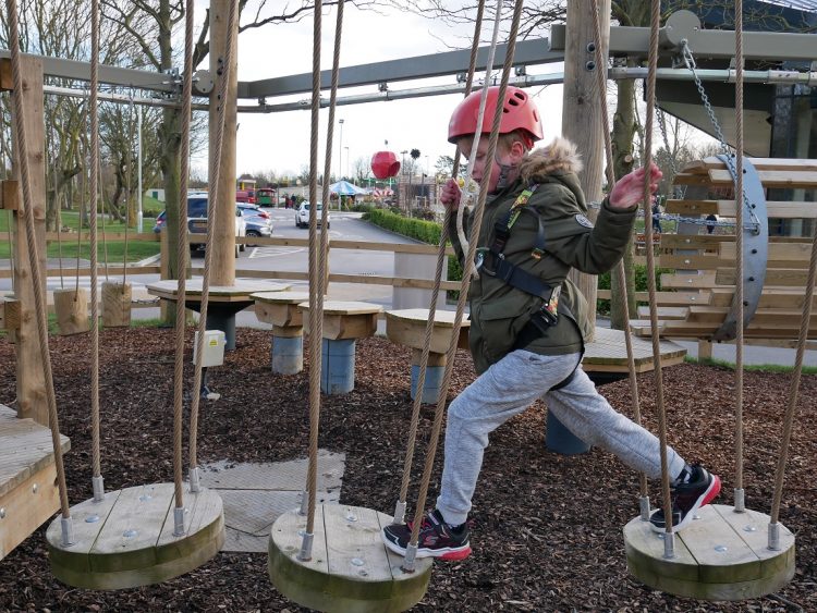 Small child with a red helmet on, playing on an adventure playground on a gloomy day