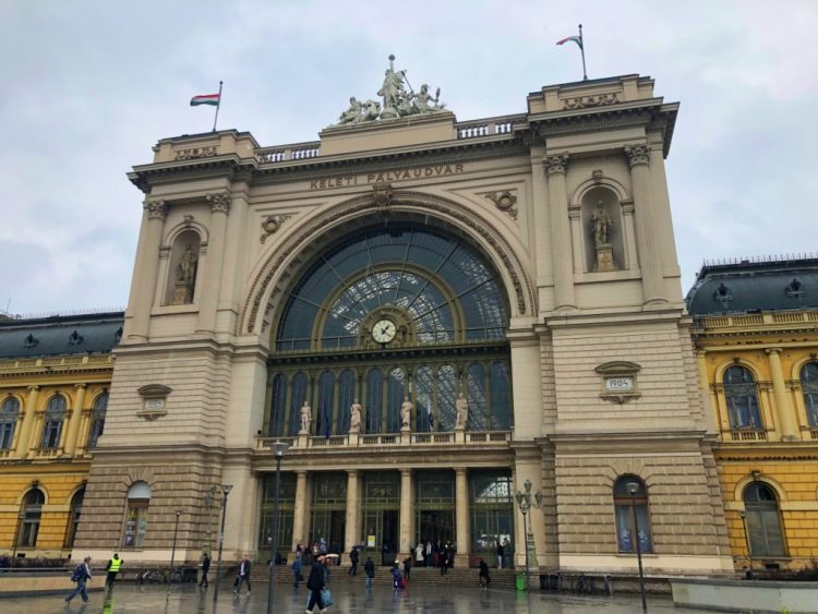 Lovely archaic Budapest train station with people coming in and out on a slightly cloudy day