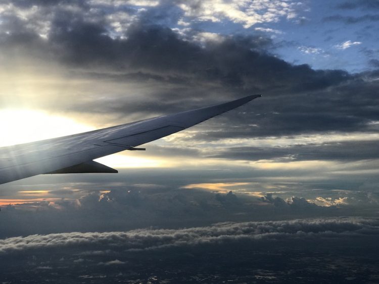 Sun shining over an airplane wing through the clouds in the sky