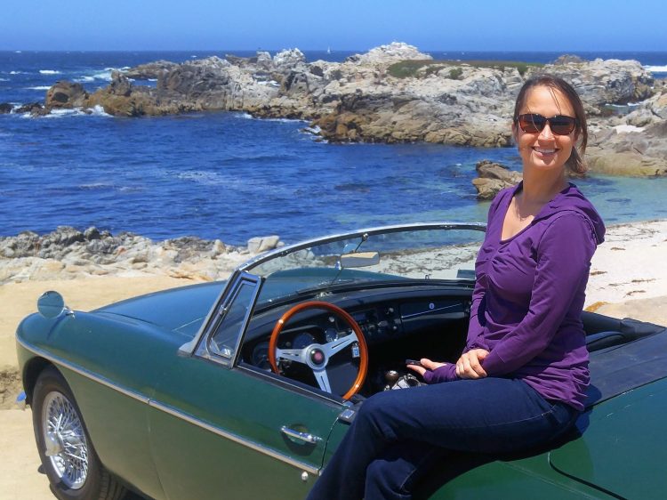 Woman sitting on a green convertible on the cliffside coast
